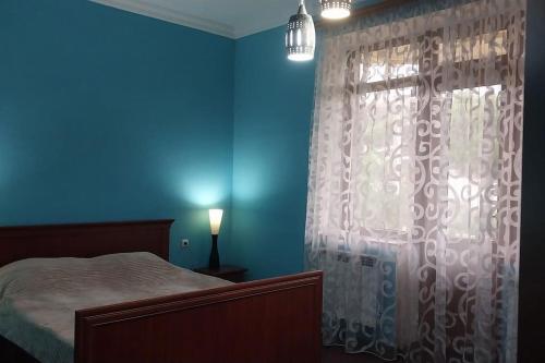 Dormitorio azul con cama y ventana en Сдается стильный особняк в Ереване! en Ereván
