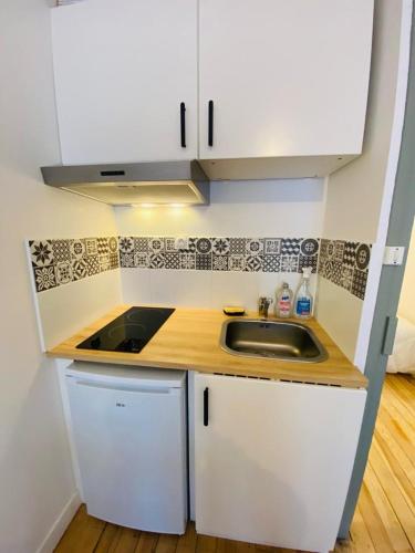 une cuisine avec des armoires blanches et un évier dans l'établissement Studio, à Cauterets