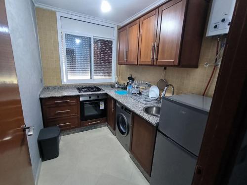 een kleine keuken met een wastafel en een vaatwasser bij Appartement Nador, Holi Flat in Nador