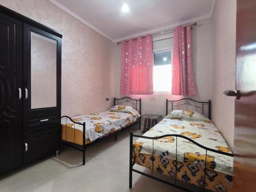 een slaapkamer met 2 bedden en een raam bij Appartement Nador, Holi Flat in Nador