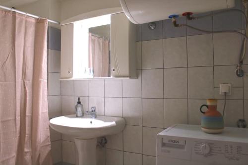 La salle de bains est pourvue d'un lavabo, de toilettes et d'un miroir. dans l'établissement Gaia Apartment, à Anatolí
