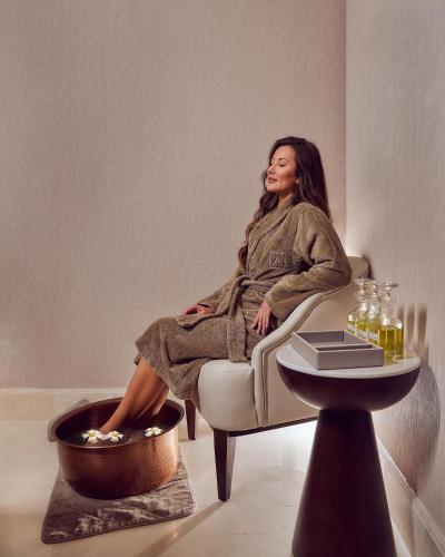 a woman sitting in a chair next to a table at Address Beach Resort Bahrain in Manama