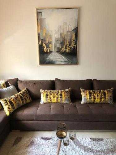 a brown couch with pillows in a living room at 5 Star Apartment Near Airport in Nouaseur