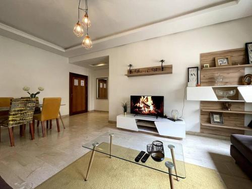 a living room with a fireplace and a table at 5 Star Apartment Near Airport in Nouaseur