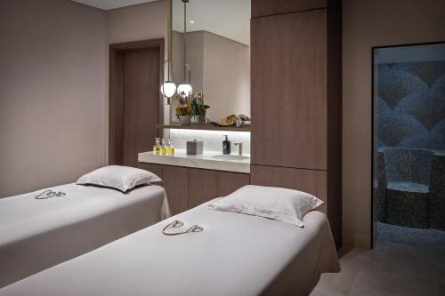 two beds in a hotel room with a sink at Address Beach Resort Bahrain in Manama