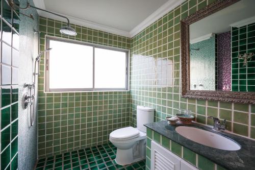 a green tiled bathroom with a toilet and a sink at At Pingnakorn Nimman Hotel in Chiang Mai