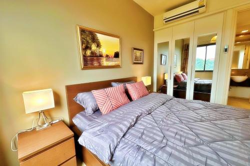 パタヤ・サウスにあるunixx city ​​center high floor amazing sea view24fのベッドルーム1室(ピンクと紫の枕が付いたベッド1台付)