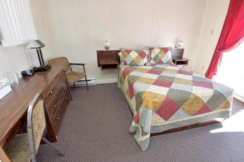a bedroom with a bed and a desk at Motel et Chalets Bo-Fleuve Evangeline in Saint-Siméon