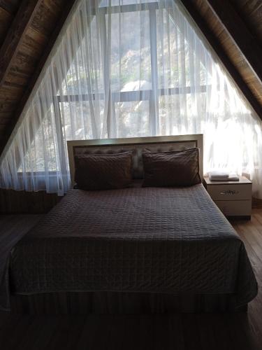 un letto in una camera con una grande finestra di Mountain Breeze a Qırızdǝhnǝ