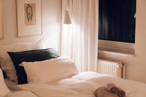 a white bed with a teddy bear sitting on it at Tallskog - Dein Apartment am Naturstrand Hohen Wieschendorf in Hohenkirchen