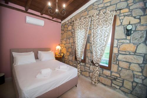 a bedroom with a bed in a stone wall at Villa Marina Limnos in Pedhinón