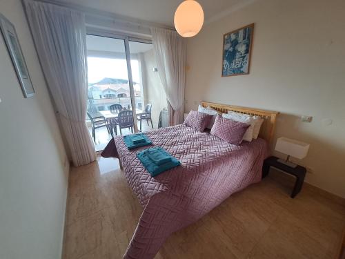Un dormitorio con una cama con sábanas moradas y una ventana en Apt. Brightness & Comfort, en Burgau