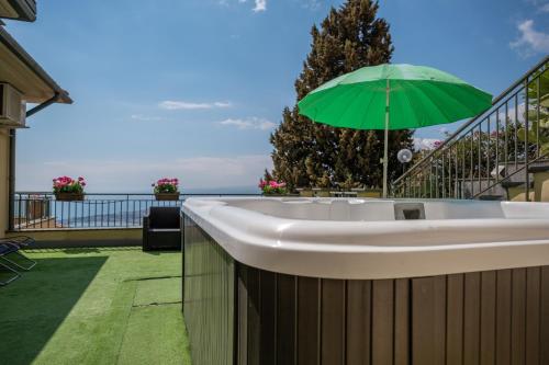 a bath tub with a green umbrella on a balcony at Villa La Gorgone in Taormina