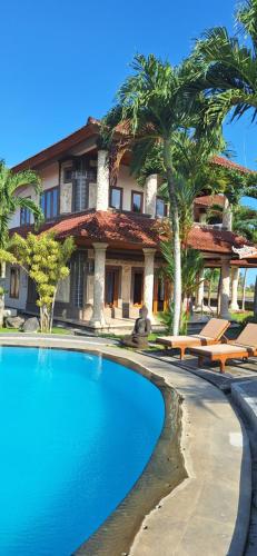 una piscina frente a un edificio con palmeras en Arbathu Villa,,, en Ubud