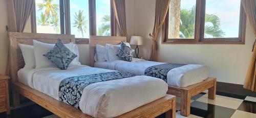 2 camas en una habitación de hotel con ventanas en Arbathu Villa,,, en Ubud