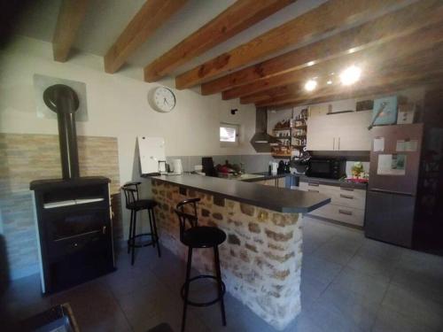 - une cuisine avec une cuisinière et un comptoir avec des tabourets dans l'établissement Ancienne Grange Landaise, à Brocas