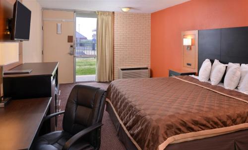 a hotel room with a bed and a desk and a television at Americas Best Value Inn - Collinsville / St. Louis in Collinsville