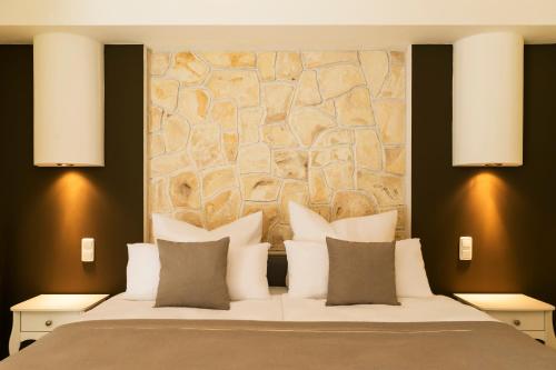 a bedroom with a large bed with a stone wall at MEMORY - Ferienapartments & Zimmer - Mediterraner Flair in der Rhön in Bischofsheim an der Rhön