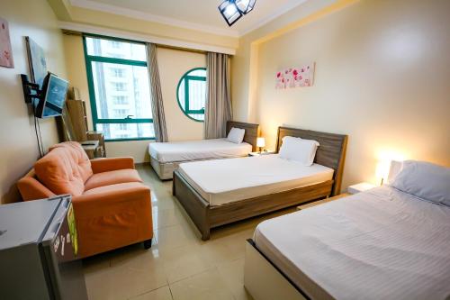 Pokój z 2 łóżkami, krzesłem i kanapą w obiekcie MC Budget Rooms for Girls Apartment Number 4202 w Dubaju