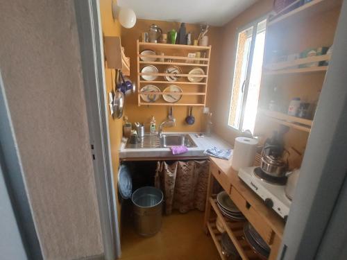 uma pequena cozinha com um lavatório e uma janela em Through the Grapevine House - peace and quiet em Egina