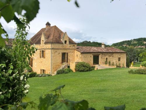 une ancienne maison en pierre avec une cour herbeuse dans l'établissement Le colombier/Piscine/Domme, à Domme