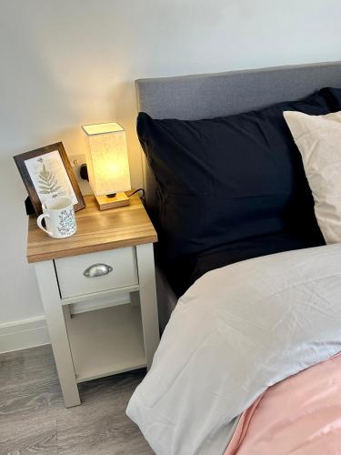 uma cama com uma mesa de cabeceira com uma chávena de café numa mesa de cabeceira em Wonderful Double Room In Wimbledon With Free Car Parking em Londres