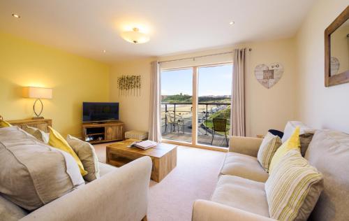a living room with a couch and a tv and a window at The Sands Sea Front Apartments in Scarborough