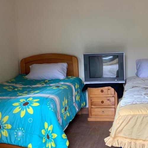 a bedroom with two beds and a tv on a dresser at Casa Campo Juive Grande in Riobamba