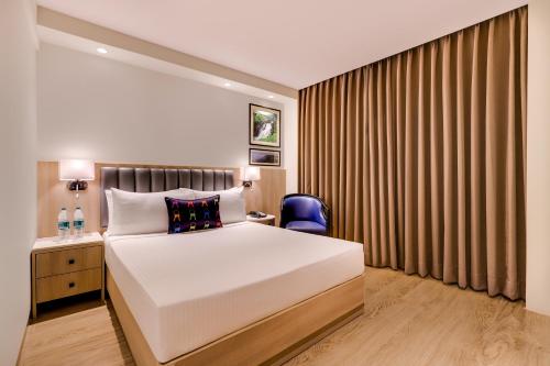 プネにあるKeys Select by Lemon Tree Hotels, Pimpri, Puneのベッドルーム(大型ベッド1台、青い椅子付)