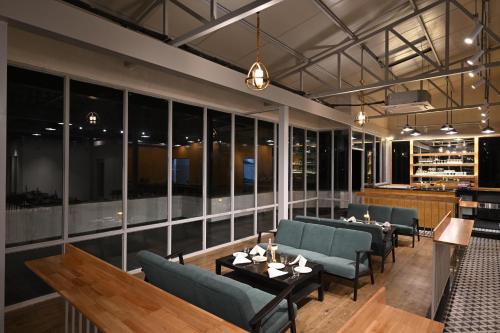 a restaurant with couches and tables and windows at Bedzzz Xclusiv Morjim, Goa By Leisure Hotels in Morjim