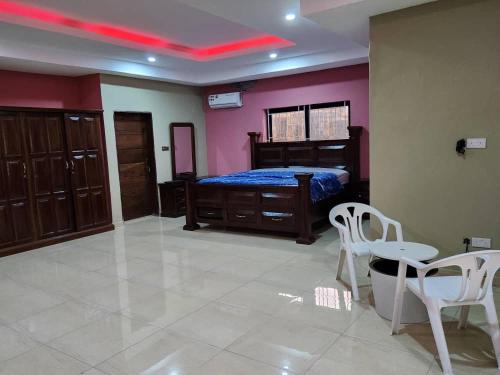 Schlafzimmer mit einem Bett, einem Tisch und Stühlen in der Unterkunft Prestigious Elegant Duplex - Abasscee in Freetown