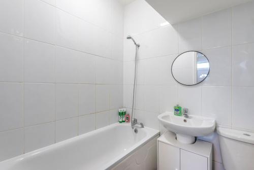 Baño blanco con lavabo y espejo en Modern family home w/Wi-Fi, Netflix, self check-in, en Londres