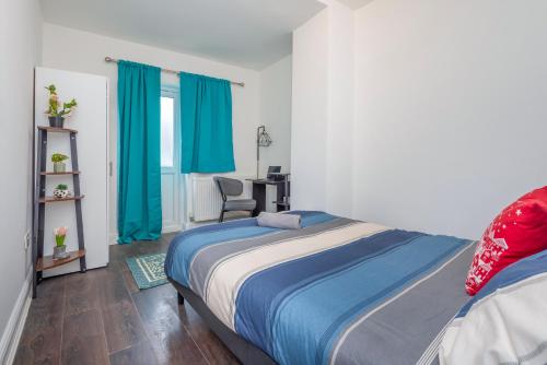1 dormitorio con 1 cama con cortinas azules y escritorio en Modern family home w/Wi-Fi, Netflix, self check-in, en Londres