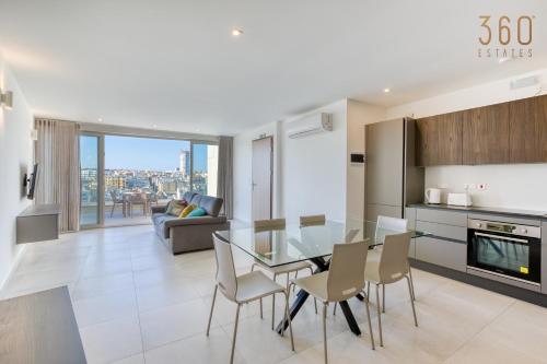 a kitchen and living room with a glass table and chairs at Modern 3BR home with Stunning Marina View in Pieta by 360 Estates in Tal-Pietà