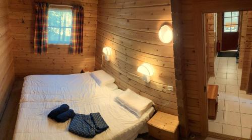 um quarto com uma cama num chalé de madeira em Le chalet Roy em Mauroux