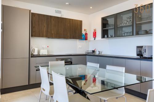 a kitchen with a glass table and white chairs at Modern 3BR home with Stunning Marina View in Pieta by 360 Estates in Tal-Pietà