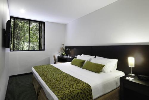 a bedroom with a large bed with green pillows at Estelar Recinto Del Pensamiento Hotel Y Centro De Convenciones in Manizales