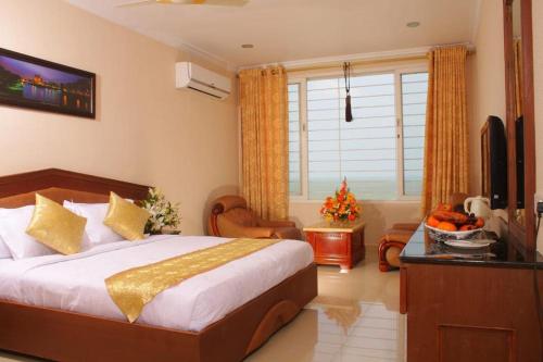 een slaapkamer met een bed, een bureau en een televisie bij THE SEASHORE HOTEL in Kanyakumari