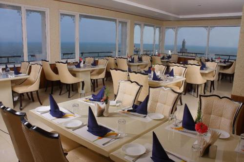 a dining room with tables and chairs and windows at THE SEASHORE HOTEL in Kanyakumari