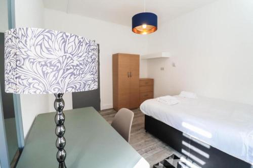 a bedroom with a bed and a table with a lamp at Urban Oasis in London