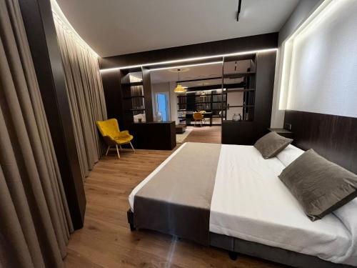 a bedroom with a large bed and a yellow chair at Hotel Reyes Ziries in Albolote