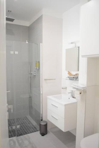 une salle de bain blanche avec une douche et un lavabo dans l'établissement Appartement Cosy et Plage, à Nice