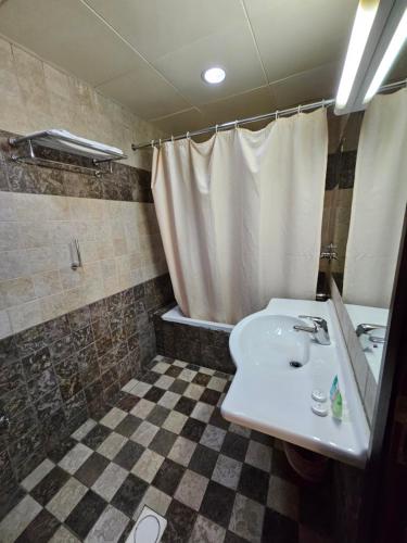 a bathroom with a white sink and a shower at Saḟeer international alkhuwair in Muscat