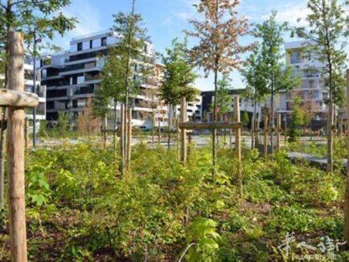 een park met bomen en struiken voor een gebouw bij welcome you in Gennevilliers