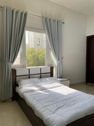 a bed in a bedroom with a large window at للإيجار استوديوهات ضمن فيلا جديده كلياً in Al Khawḑ