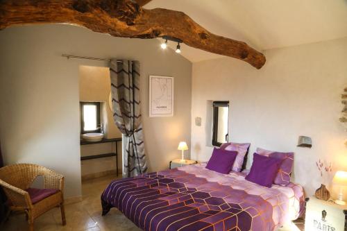 - une chambre avec un grand lit et des oreillers violets dans l'établissement Grand Gite, Mas Favières, à Notre-Dame-de-la-Rouvière