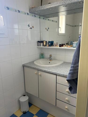 ein weißes Badezimmer mit Waschbecken und Spiegel in der Unterkunft Les trois îles O.Ré.A. in Aytré