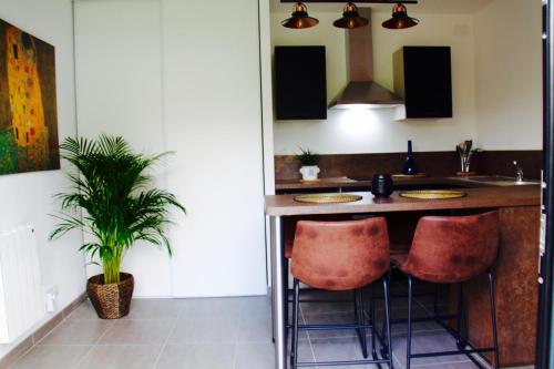 une cuisine avec un îlot et deux tabourets de bar dans l'établissement Le petit gîte de Cancale, Saint-Malo, Bretagne, à Cancale