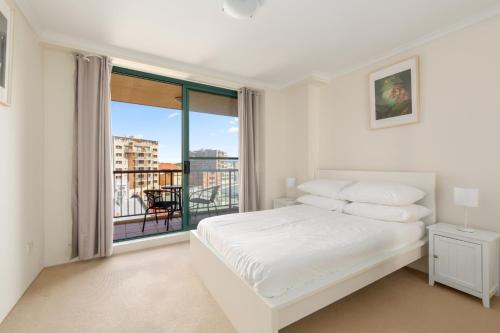 a white bedroom with a bed and a large window at Spacious 3-Bed with Alfresco Dining by Amenities in Sydney