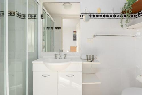 a white bathroom with a sink and a shower at Spacious 3-Bed with Alfresco Dining by Amenities in Sydney
